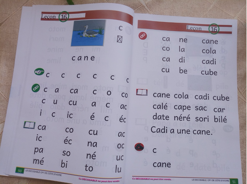 An open textbook showing letters, phonemes, and words